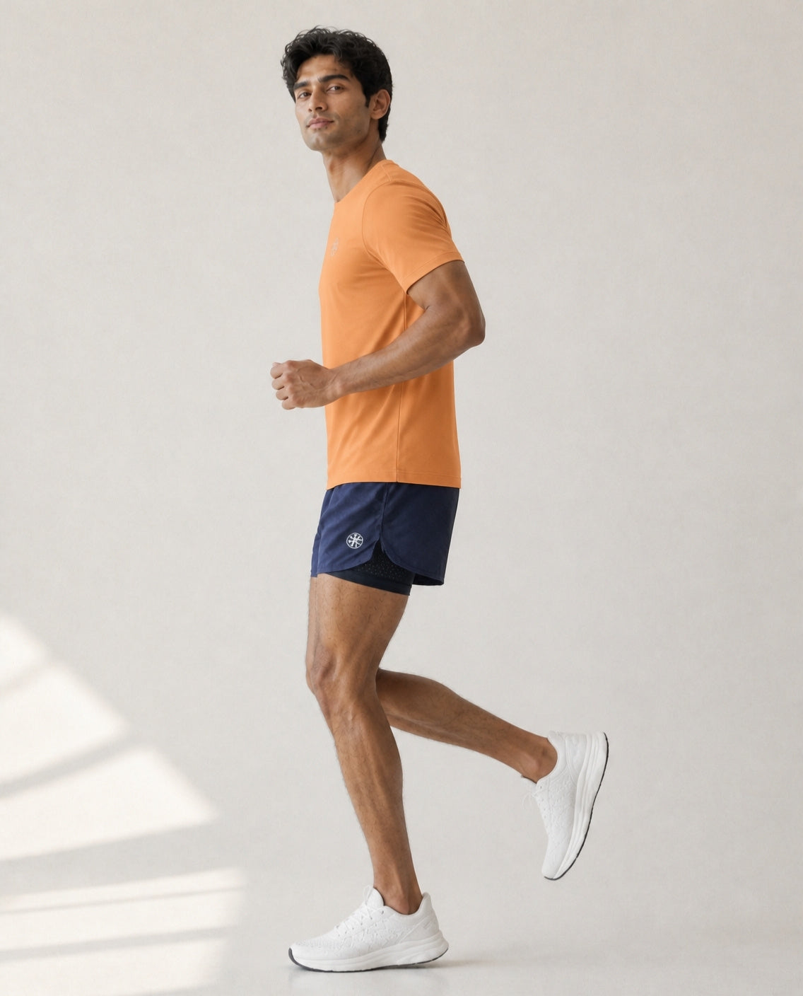 Athleia Sprintlite Shorts Navy with Pro Tee Orange, side view showing liner – worn by a man